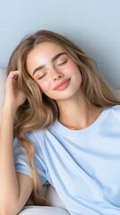 Fototapeta premium Serene Young Woman with Long Flowing Hair Relaxing at Home, Embracing Tranquility in a Soft Light Blue T-Shirt Against a Gentle Blue Background for a Calming Atmosphere