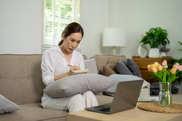 A woman is sitting on a couch with a laptop open in front of her