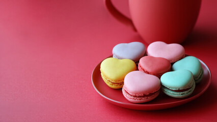 Obraz premium Colorful macaroons in the shape of hearts on a pink background