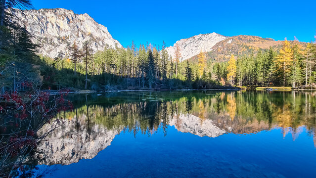 Lake Kreuzteich surrounded by mountain peak Messnerin in Hochschwab Alps, Tragoess, Styria, Austria. Forest in vibrant autumn foliage. Crystal-clear water reflects majestic ridges. Mirror-like effect