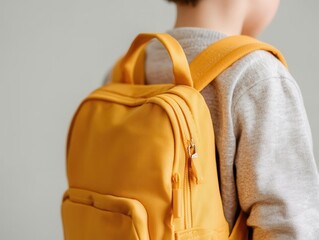 A young child wearing a yellow backpack, showcasing a casual and playful style, against a neutral background.