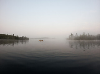 Tandem canoe paddling in a misty morning on the lake in the Boundary Waters (BWCA)