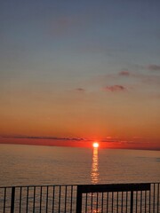 Genova, Italy - December 29, 2024: Background of beautiful sunset over Mediterranean sea waves. Selective focus. Beautiful red and orange sunrise over the sea. Beautiful seascape scenery, Amazing ligh