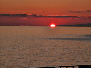 Genova, Italy - December 29, 2024: Background of beautiful sunset over Mediterranean sea waves. Selective focus. Beautiful red and orange sunrise over the sea. Beautiful seascape scenery, Amazing ligh