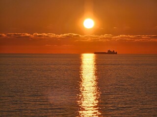Genova, Italy - December 29, 2024: Background of beautiful sunset over Mediterranean sea waves. Selective focus. Beautiful red and orange sunrise over the sea. Beautiful seascape scenery, Amazing ligh