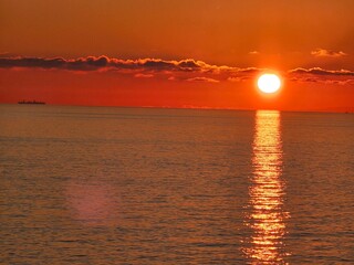 Genova, Italy - December 29, 2024: Background of beautiful sunset over Mediterranean sea waves. Selective focus. Beautiful red and orange sunrise over the sea. Beautiful seascape scenery, Amazing ligh