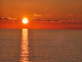 Genova, Italy - December 29, 2024: Background of beautiful sunset over Mediterranean sea waves. Selective focus. Beautiful red and orange sunrise over the sea. Beautiful seascape scenery, Amazing ligh