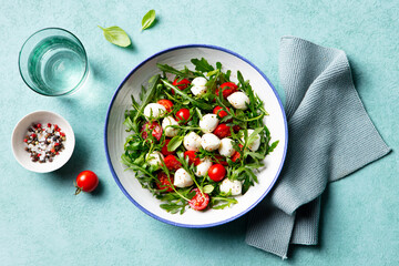 Fresh salad with cherry tomatoes, mozzarella cheese and arugula. Close up. Top view.