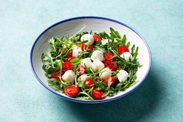 Fresh salad with cherry tomatoes, mozzarella cheese and arugula. Close up.