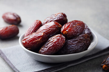 Fresh medjool dates in bowl. Grey background. Close up.