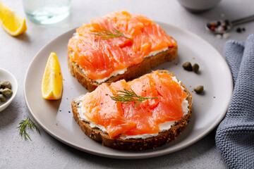 Sandwich, toast with smoked salmon and cream cheese on plate. Grey background. Close up.