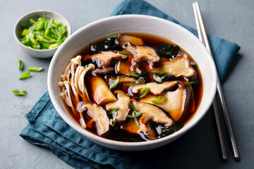 Miso soup with mushrooms. Traditional Japanese food. Grey background. Close up.