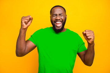Photo of bearded overjoyed ecstatic man having won some competitions while isolated with yellow...