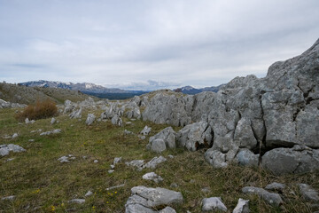 Mountaintop landscape with rocky terrain and distant peaks under a cloudy sky