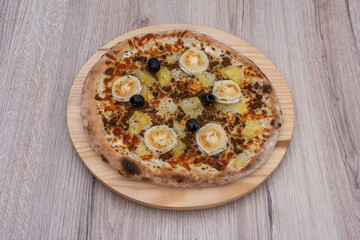 Paris, France - 11 06 2023: Italian culinary Still Life. A farmhouse pizza with potatoes, chorizo, olives and cheese seen from above and placed on a wooden tray.