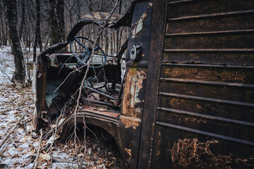 Old vintage rusty van abandoned on a snowy forest.