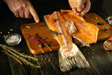 Culinary enthusiasts skillfully prepare fresh fish on a wooden cutting board, surrounded by herbs...
