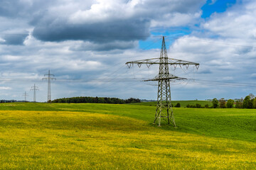 Stromtrasse auf einem Feld unter weiß-blauem Himmel