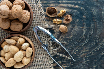 Pliers for splitting nuts and assorted nuts in a wooden bowls. Top view