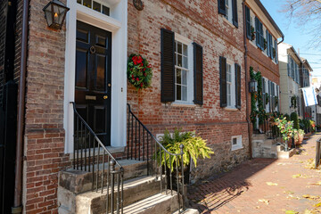 Traditional Christmas wreath on the front door of a brick house.
