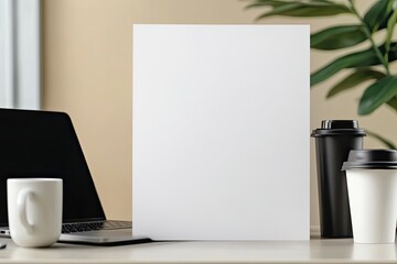 Fototapeta premium close-up of blank poster placed on neutral desk surrounded by laptop and coffee cup for professional feel