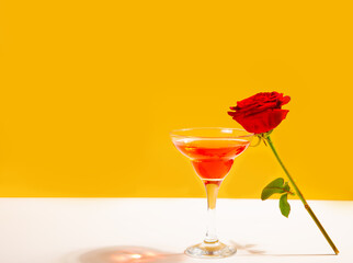 Glass of red wine with red rose on the white background. Romantic date concept.