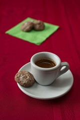 A shot of espresso with a group of espresso coin cookies on a green napkin.