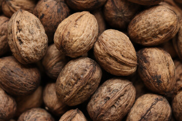 Heap of walnuts in shell, close-up, top view. Healthy eating. Harvest, agriculture. Walnuts, selective focus, background