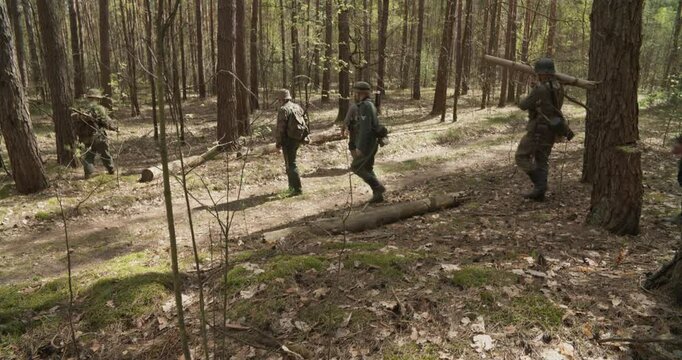 Reenactors Dressed As German Infantry Soldiers Marching By Forest Autumn Season. Group Of Soldiers With Carabines Mauser 98k, Panzerschreck Bazooka Combing Forest. Reenactment Tactic Game. Wermacht