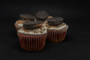 close up of various sweet cupcakes on cake stand isolated on black