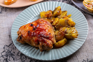 Crispy chicken pieces baked with potatoes in spices on a plate