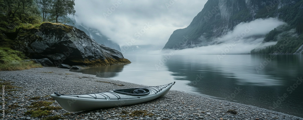 Poster resting kayak on a calm pebble beach in a tranquil fjord surrounded by towering mountains and misty 