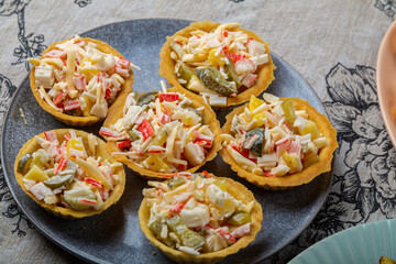 Salad with crabs and pineapples in tartlets on a plate decorated