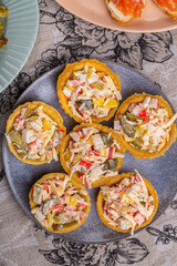 Salad with crabs and pineapples in tartlets on a plate decorated with cilantro