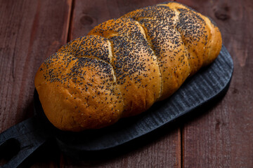 Traditional Jewish holiday challah with poppy seeds on a table on a wooden board