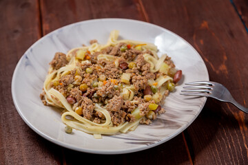 Udon with minced meat and vegetables in sauce in a plate on the table