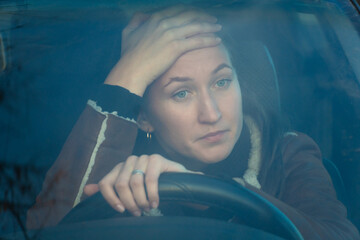 Young woman driving a car experiences stress and frustration while driving in traffic, clutching...
