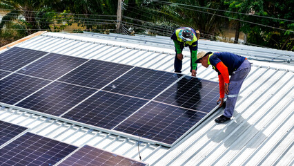A sustainable energy project featuring solar panels on a roof surrounded by tropical trees, highlighting renewable energy efforts and the integration of green technology into rural areas.