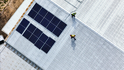 A sustainable energy project featuring solar panels on a roof surrounded by tropical trees,...