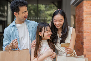 Obraz premium Joyful Family Shopping Experience with Credit Card in Modern Retail Setting