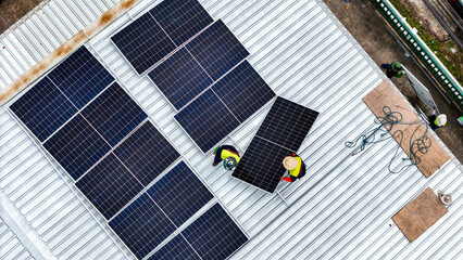 A sustainable energy project featuring solar panels on a roof surrounded by tropical trees,...