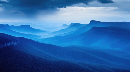 Obraz premium Majestic blue mountains under a dramatic sky capturing the serene beauty of nature in landscape photography.