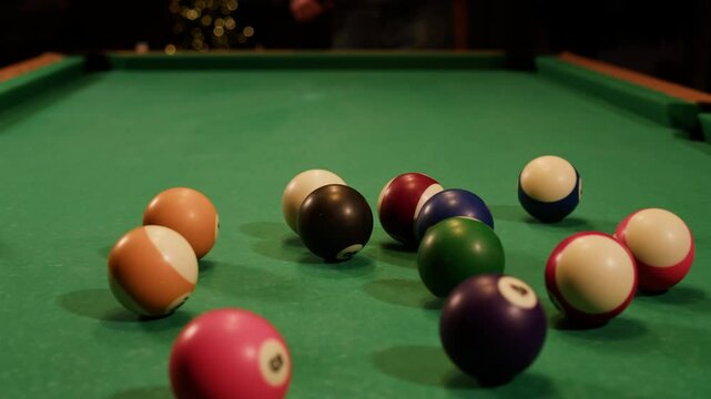 Young man playing American billiard pool poule close-up. Colorful balls on green billiards table .Billiard balls with numbers on a pool table. Billiards team sport.