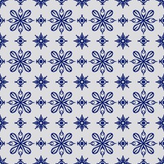 Seamless pattern featuring intricate blue floral and ornamental motifs arranged symmetrically on a light background, creating an elegant tile design.