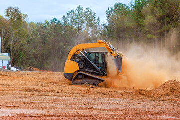 Construction vehicle prepares plot of land by moving dirt amid dust trees for future development...