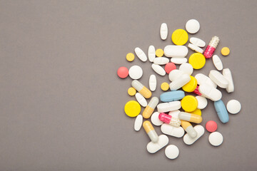 Various colored pills on grey background. Space for text