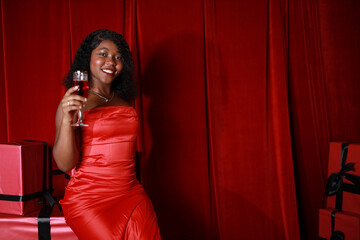 Naklejka premium beautiful happy female with glass of champagne on red background 