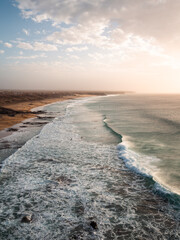 Vertical shot capturing a dramatic coastal scene with towering ocean waves