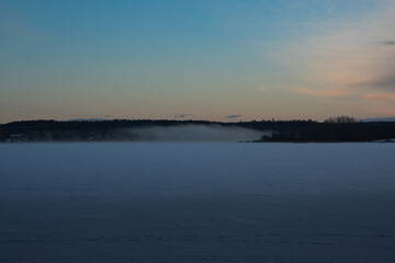Misty current by the lake in a wintery scenery during sunset.