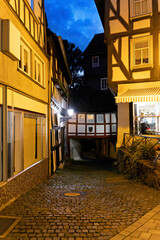 illuminated city center street with half-timbered houses in Wetzlar on the Lahn with shops, lamps and reflections